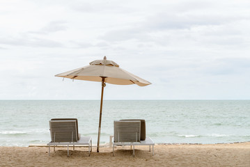 empty two beach chairs and umberella on a beautiful beach at sunny day - vacation in summer time
