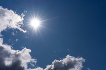 bright sun in clear sky with few clouds. contrast photo deep blue sky and sun. Copy space