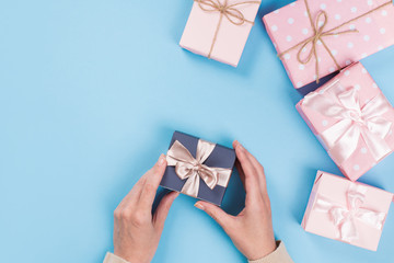 Womans hands holding gift or present box on blue pastel table. Flat lay  for birthday or New Year.