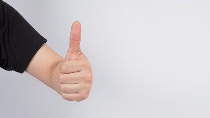 Male's left hand doing thumbs up sign on white background.