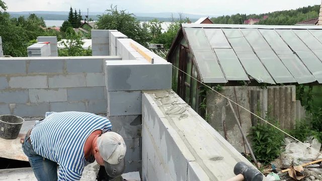 Bricklayer putting down another row of bricks in site