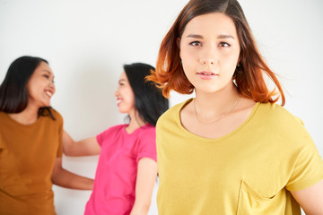 Portrait of young beautiful woman in T-shirts looking at camera with other two girls in the background they standing over white background