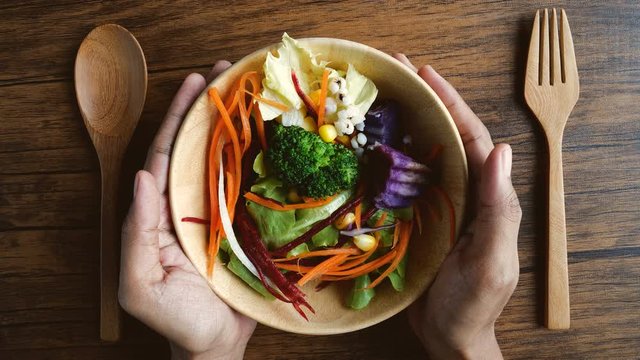 Close up hand hold mixed of colorful vegetable in wooden bowl on the table , vegan healthy organic food for diet and control weight loss