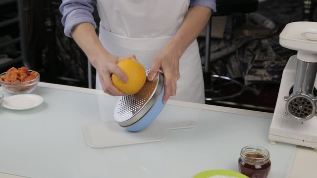 confectioner cuts the orange peel, citrus zester grating peeling orange peel
