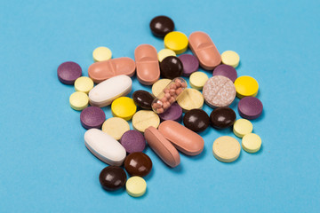 many scattered Colorful medical pills on pastel blue background