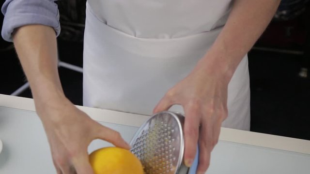 confectioner cuts the orange peel, citrus zester grating peeling orange peel