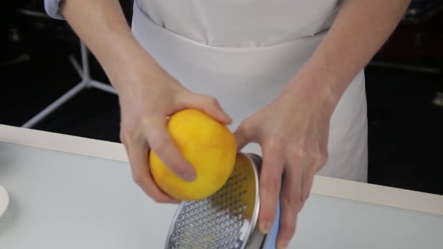 confectioner cuts the orange peel, citrus zester grating peeling orange peel