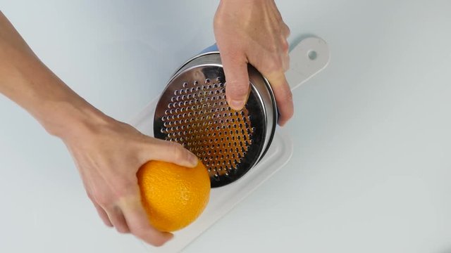 confectioner cuts the orange peel, citrus zester grating peeling orange peel. 4K top view
