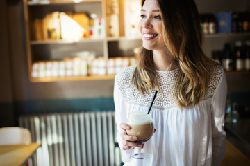 Beautiful smiling woman drinking coffee at cafe, home, at work