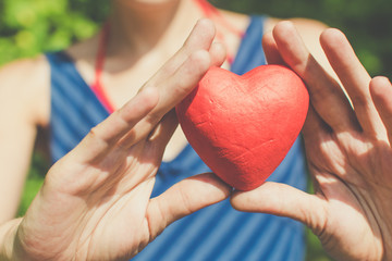 Relationship and love concept - womans hands holding red heart