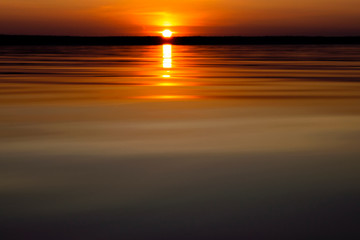 Water surface. View of a Sunset sky background. Dramatic gold sunset sky with evening sky clouds over the sea. View of a Crystal clear sea water texture. Landscape. Small waves. Water reflection