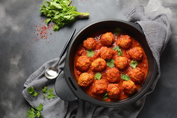 Meatballs in sweet and sour tomato sauce with spices served in a frying pan on dark background . Top view 