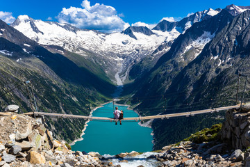 Hiker with dog looking at view of Schlegeisspeicher from Olperer Hutte bridge