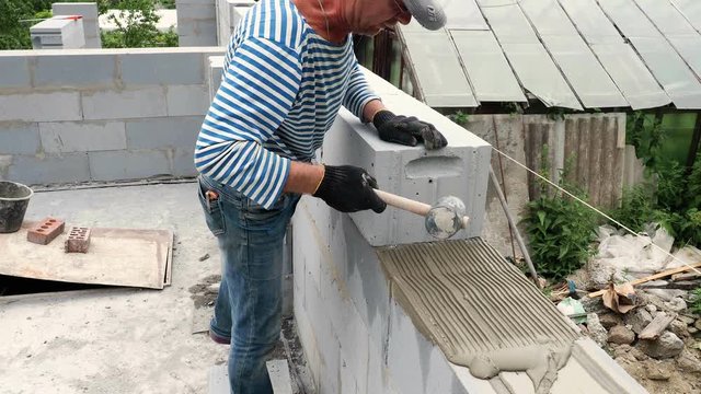 Bricklayer putting down another row of bricks in site