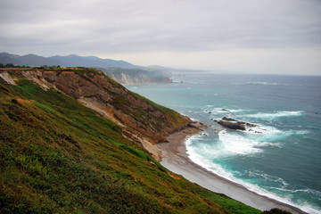 Fototapeta na wymiar Rocky cliff next to a sea on a rainy day.