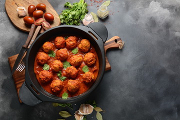 Meatballs in sweet and sour tomato sauce with spices served in a frying pan on dark background . Top view 
