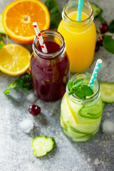 Various refreshments drinks - detox cucumber water, cherry juice and orange juice on stone table. Copy space for your text.