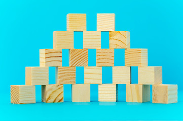 Pyramid semicircle of wooden cubes, close-up, place your advertising slogan on a blue background.