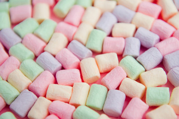 Colorful mini marshmallows on pink background