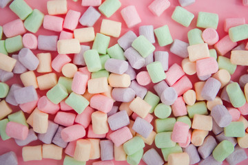 Colorful mini marshmallows on pink background