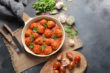 Meatballs in sweet and sour tomato sauce with spices served in a frying pan on dark background . Top view 