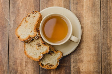 Tea cup and pastries piece on wooden table. Breakfast. Top view