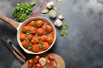 Meatballs in sweet and sour tomato sauce with spices served in a frying pan on dark background . Top view 