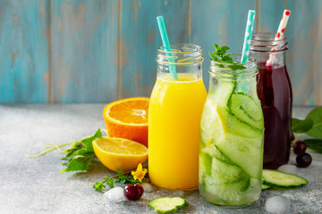 Various refreshments drinks - detox cucumber water, cherry juice and orange juice on stone table. Copy space for your text.