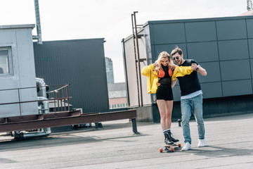 attractive woman skateboarding and man in glasses hugging her