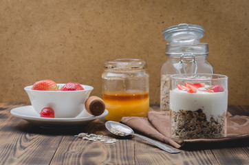 Healthy breakfast. Yogurt, fresh strawberry, honey, spoon with the scattered granule on a wooden...