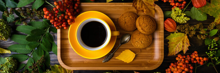 Cup of coffee and cookies on autumn wooden background. Autumn leaves and berries on background. Concept cozy coffee cup, autumnal warm breakfast. Long format