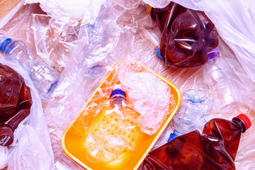 Lot of used plastic, crumpled empty bottles, packets, plastic orange dish, diaper, pollution recycle eco concept background close up selective focus