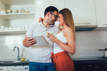 Young couple using digital tablet in the kitchen