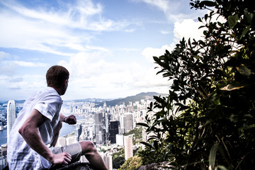 Fototapeta na wymiar Vue homme de dos assis de la baie de Hong Kong et des grattes ciel