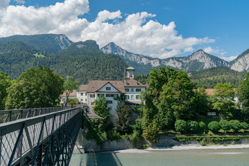 Fototapeta na wymiar Reichenau Castle and bridge over the Rhine with the Swiss Alps in the background