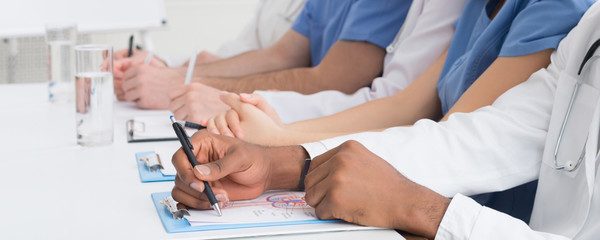 Medical education. African-american doctor writing notes closeup