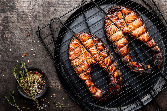 Grilled salmon on iron grill grate on a dark background top view. BBQ seafood. spece for a text
