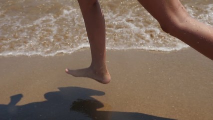 Slow motion of female legs running splashing into water.