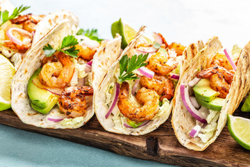 Shrimp tacos. Seafood fajitas with cabbage, onion, parsley in tortillas served on wooden cutting...