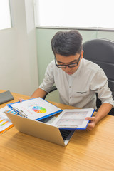 Fototapeta na wymiar Vertical photo of Asian office man reading financial report