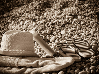 Sun hat and flip flops on stone beach