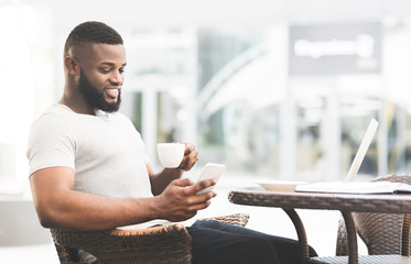 Handsome african man drinking coffee and reading
