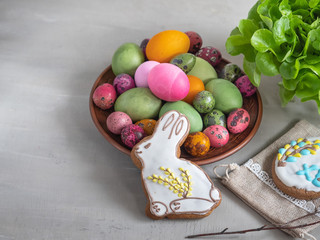 Easter set of gingerbread Bunny shape, colorful eggs on a light background, a cloth of burlap and a dry twig, taken from close range