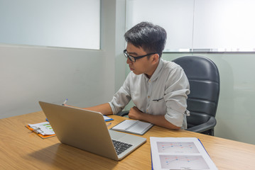 Serious young businessman looking report in office