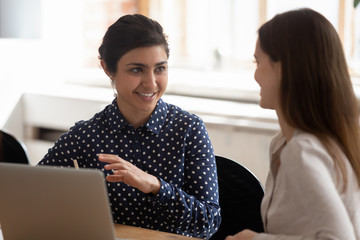 Smiling multiethnic girls talk studying at project together