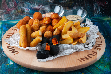 various snacks on the table, cheese plate, deep-fried cheese sticks, cheese balls, french fries. beer snack