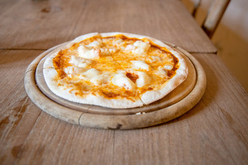Home made Crispy Thin Cheese and Shrimp Pizza Hot Served on a wooden plate Placed on a wooden table.
