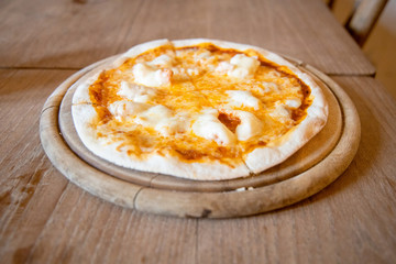 Home made Crispy Thin Cheese and Shrimp Pizza Hot Served on a wooden plate Placed on a wooden table.