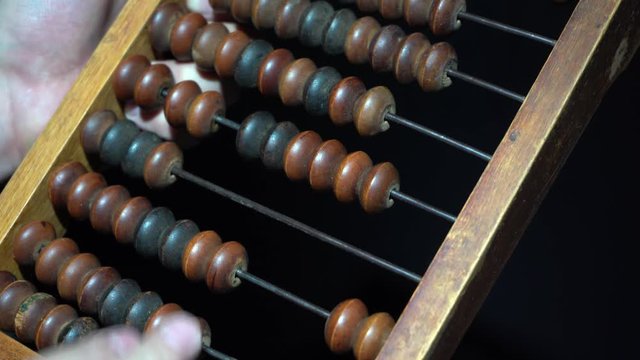 Man uses vintage old abacus . Male hand on vintage wooden bills close-up.