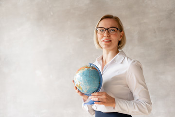 Charming teacher wearing blouse and skirt holds globe her hands